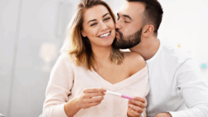 Fertilidade do casal: homem e mulher segurando um teste de gravidez de farmácia, comemorando o positivo para gestação.