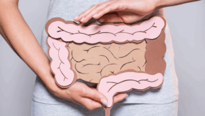 Figura de um intestino, em frente ao abdômen, segurado pela própria pessoa pelas suas duas mãos para ilustrar a ideia de microbiota intestinal.