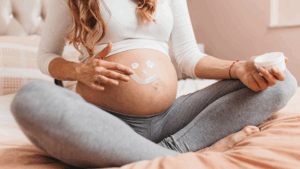 Mulher grávida sentada com um desenho de carinha feliz na barriga, mostrando como prevenir doenças crônicas na gravidez.